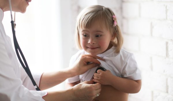 Cardiologist listens to the heart of a child with Down syndrome, the concept of health and medical examination of children with special needs